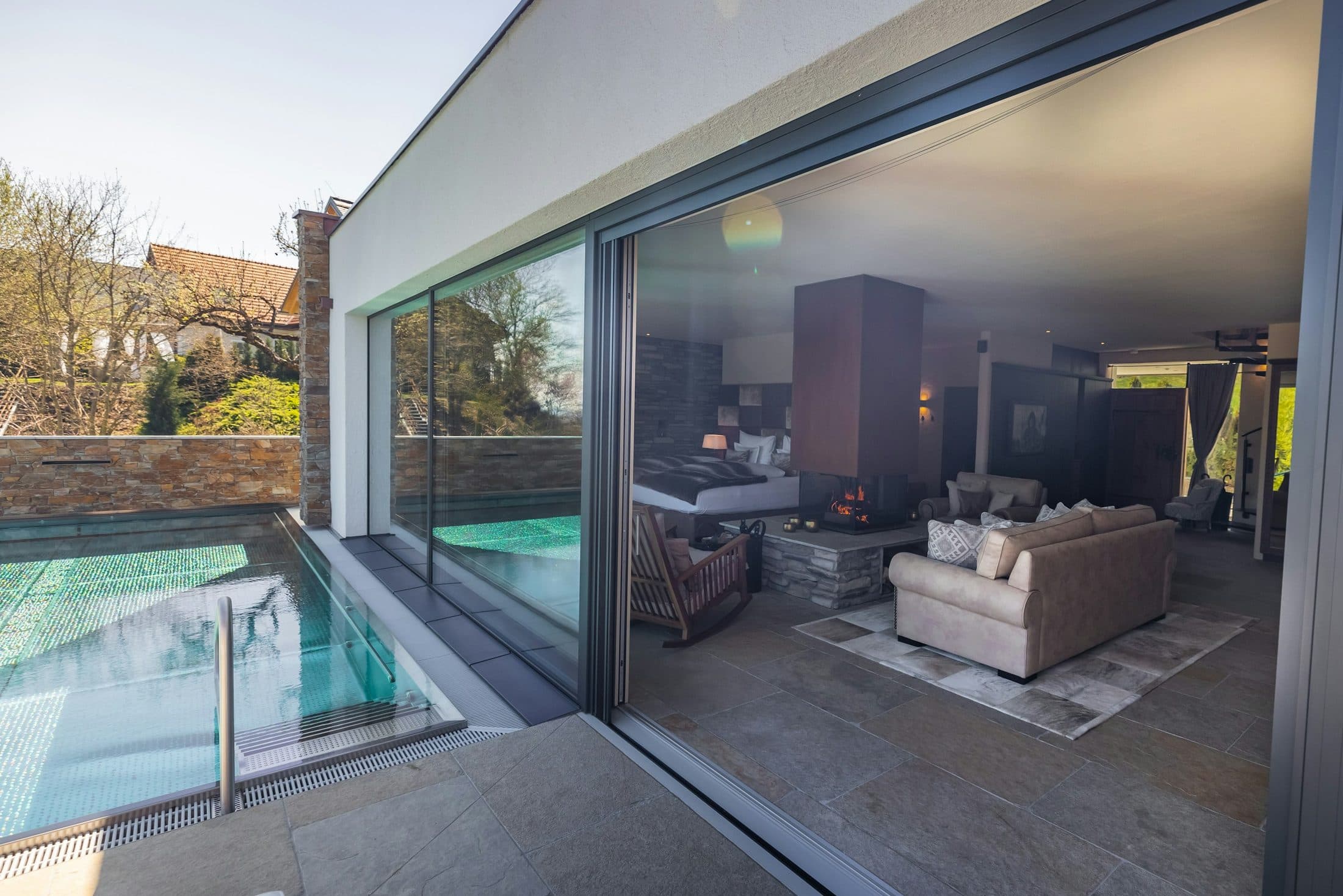 Une grande baie vitrée coulissante à cadre aluminium sombre, ouverte sur un salon et une terrasse