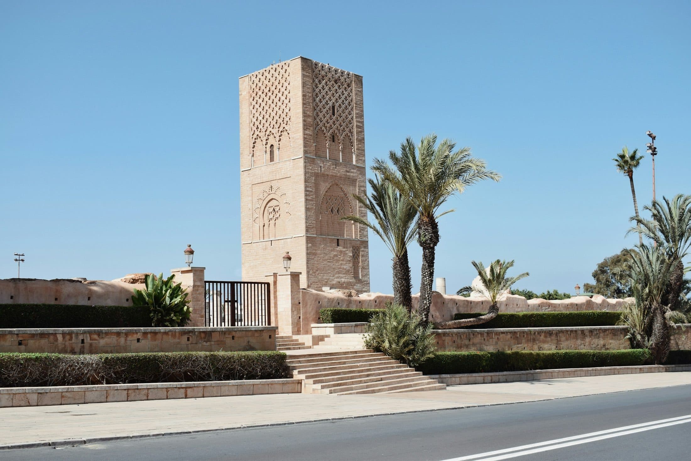 La Tour Hassan à Rabat, minaret en pierre ocre entouré de palmiers sous un ciel bleu